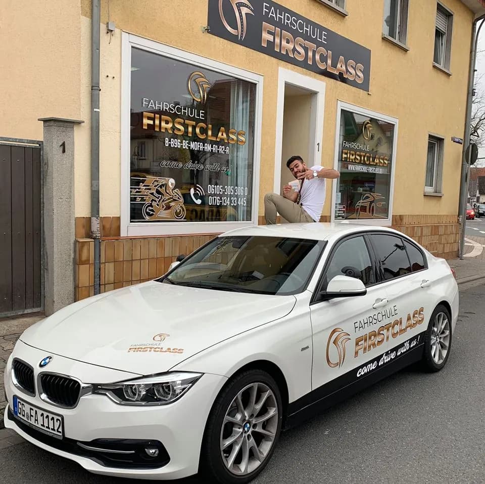 Weißer BMW der Fahrschule FirstClass vor dem Schaufenster
