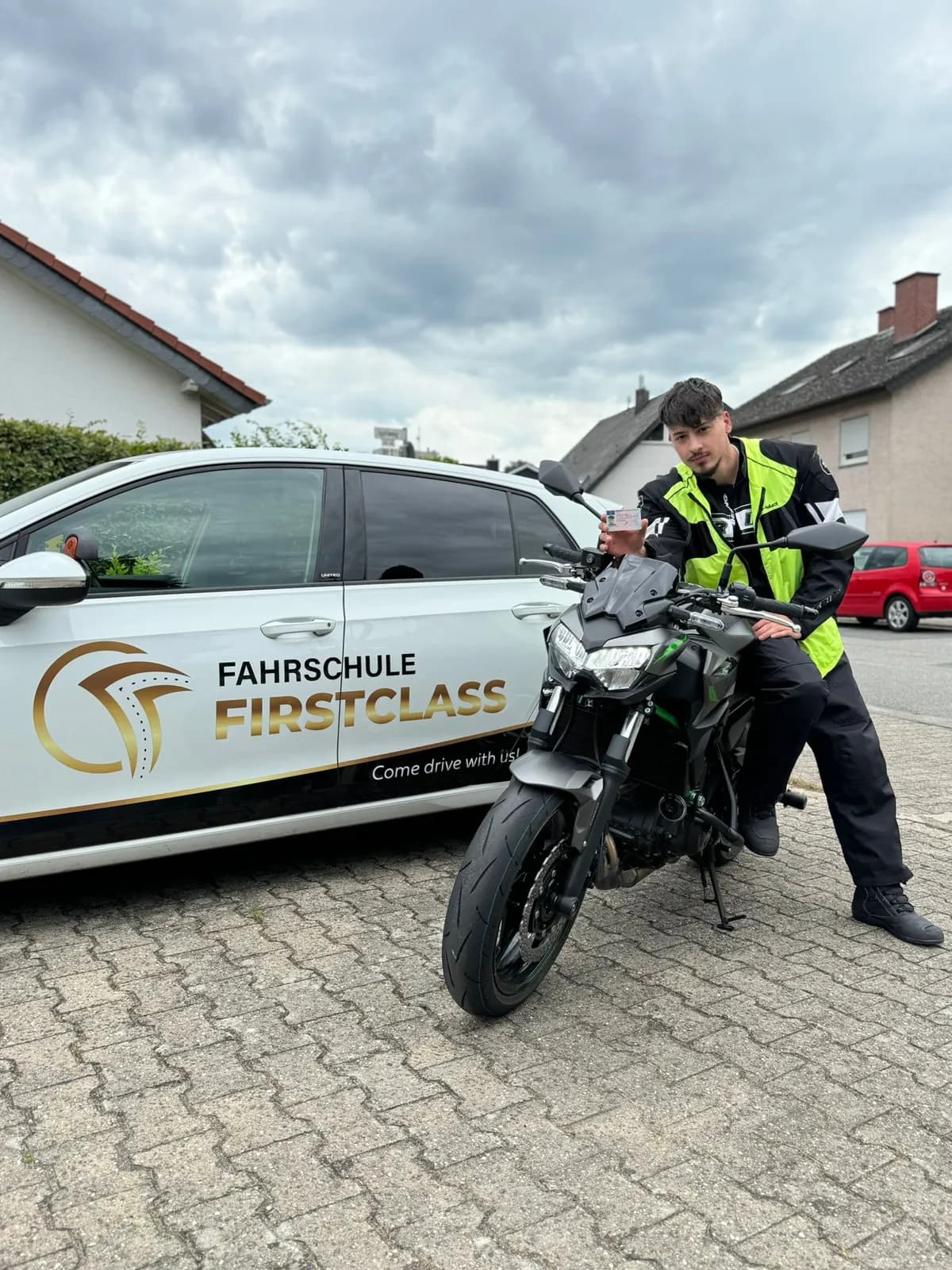 Motorradausbildung mit Warnweste vor dem Fahrschulauto